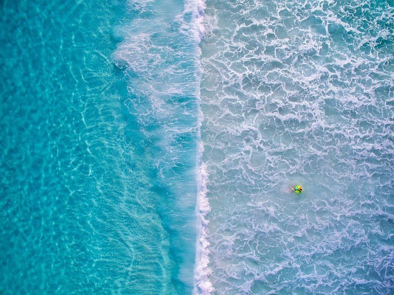 海灘水面的鳥瞰圖，浪花剛好將畫面劃分為左右兩半。（圖片來源：Kirk Hille / Skypixel.com）
