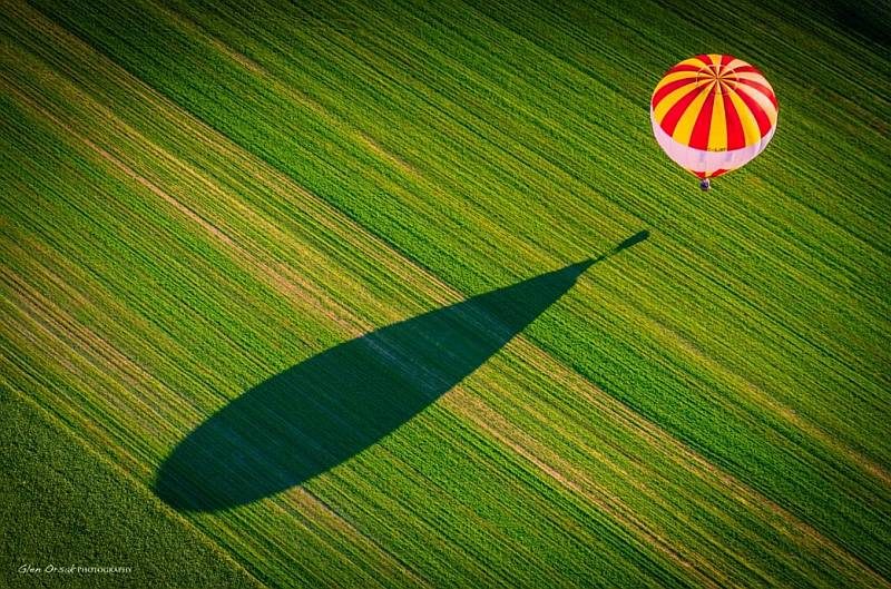 一大片留白的大草原，讓空中熱氣球的影子有長長的投射在地面上，令畫面變得更為壯觀。