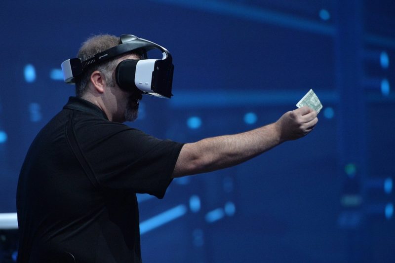 戴上 Project Alloy 眼鏡 的 Intel 工作人員示範如何在虛擬世界中展示手中的鈔票。